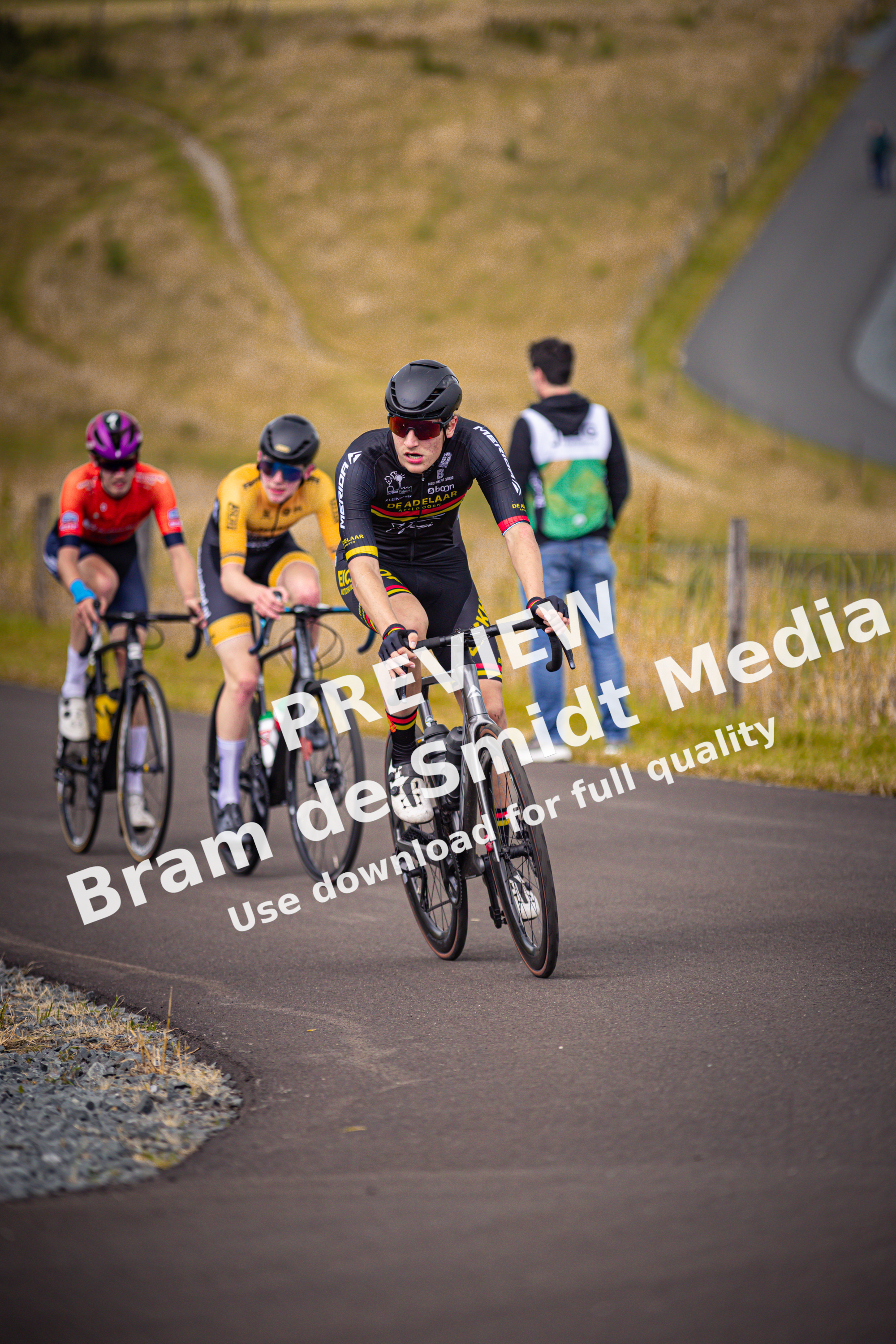 A group of cyclists in a race, wearing helmets and black and red uniforms.