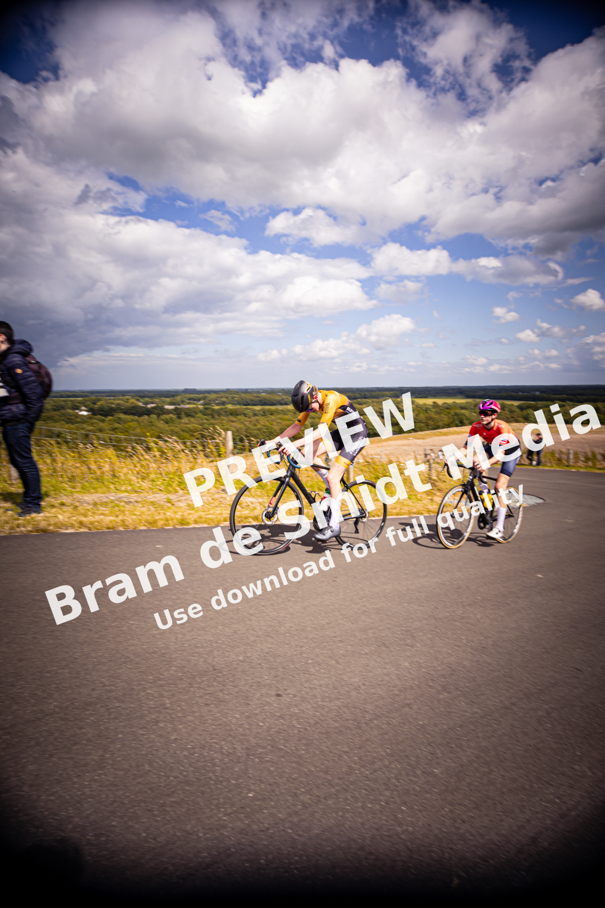 A group of cyclists are on a road near a blue sky.