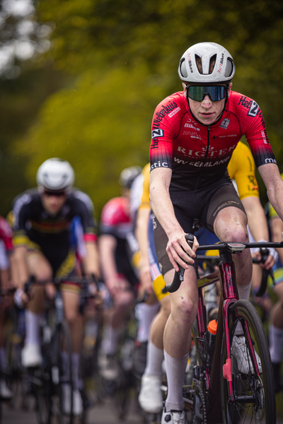 A male cyclist wearing a red and black jersey sponsored by Rikkia.