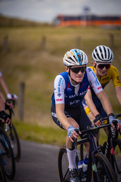 A cyclist with a blue and white shirt racing another cyclist in the 2024 Nederlands Kampioenschap.