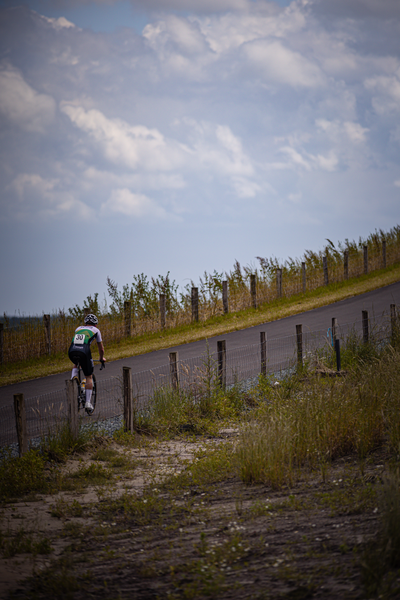 A cyclist on a paved road with a white shirt and green bike.