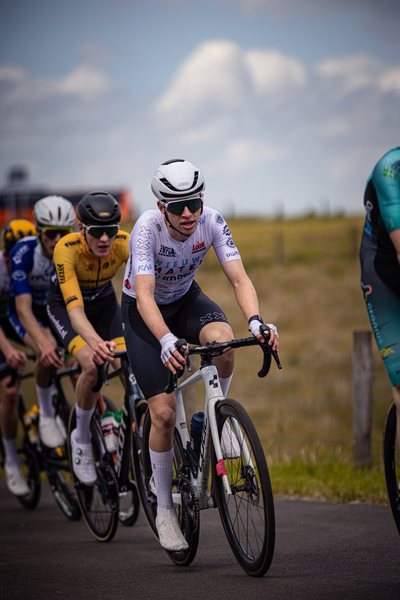 The cyclists are participating in a race, one of them is wearing a black outfit with the number 24 on it.