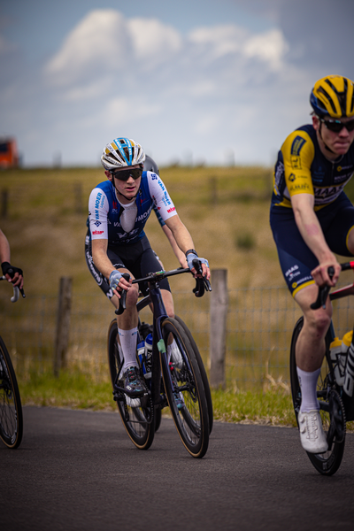 Two cyclists racing down a street with one wearing a blue and black jersey.