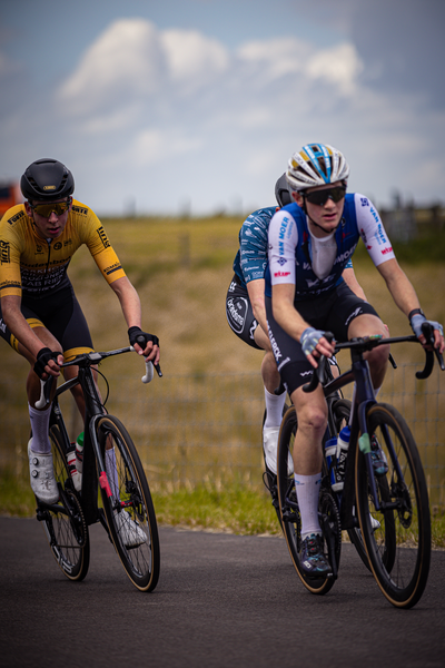 Two cyclists on a road wearing blue and white uniforms.