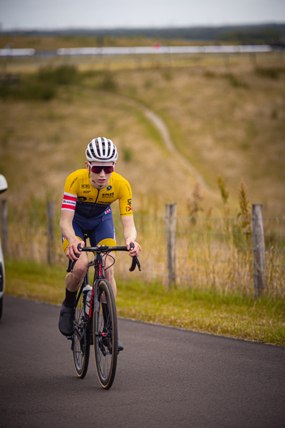 A person riding a bike wearing a yellow shirt and blue shorts.