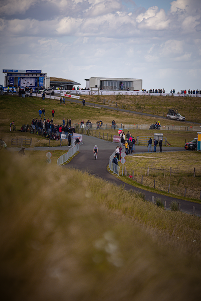 A group of people, some on bikes, are gathered at the Nederlands Kampioenschap event.