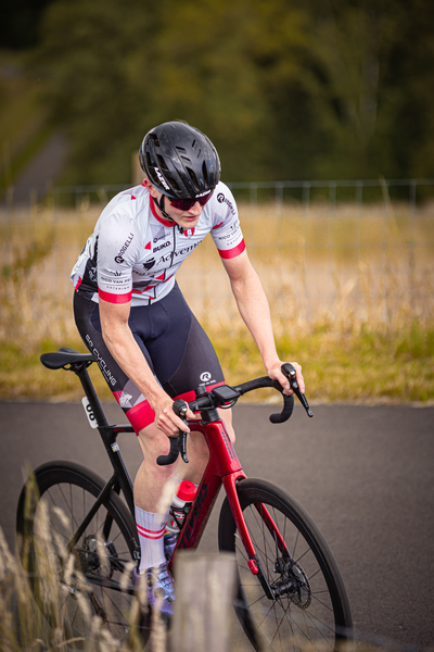 A person riding a red bicycle with the words "Junioren Mannen" on it.