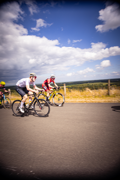 Three cyclists in a race, one is wearing red and black.