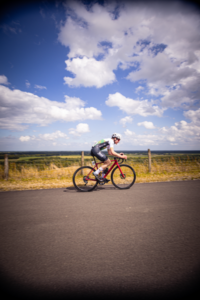 A man wearing a number 2 jersey rides his bike down the road.