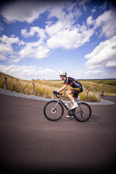 A young man in a black and red jersey is riding his bike.