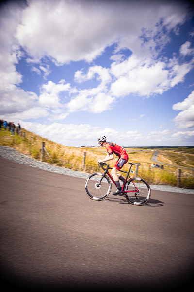 A man in a red jacket rides his bike along a path.