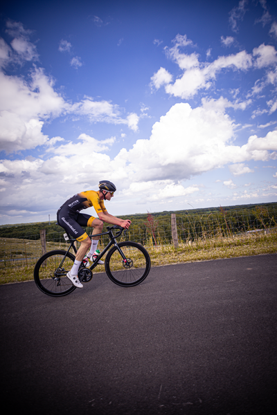 a man wearing a yellow and black shirt riding a bicycle.