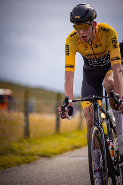 A male cyclist in a yellow jersey with the number 23 on it.