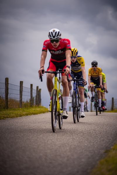 Four cyclists are riding down a road in the Netherlands.