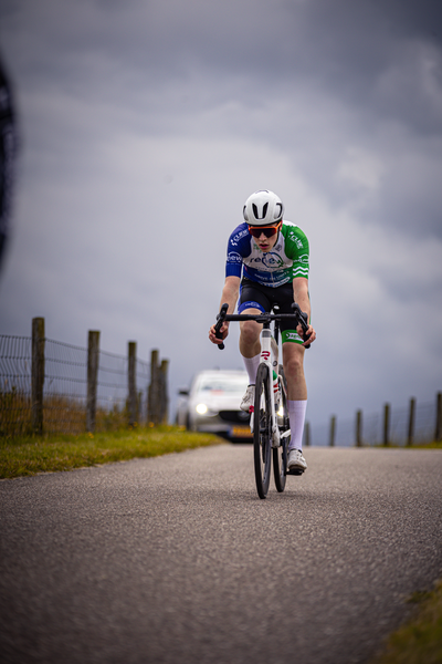 A bicyclist wearing a blue and white shirt with the number 10 on it races down a road.