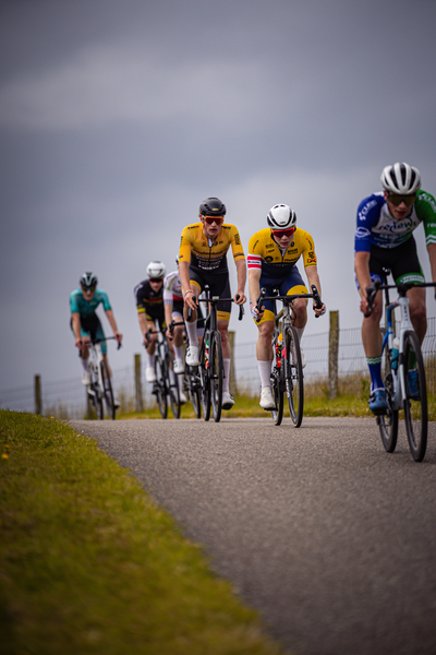 A man with a yellow shirt and blue shorts riding his bike in the lead.