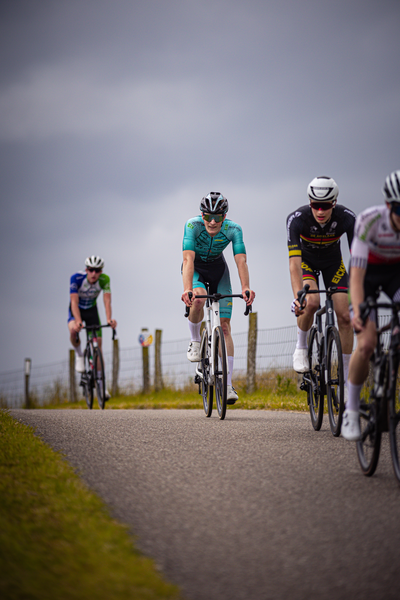 A group of cyclists are riding on a road during the Nederlands Kampioenschap.