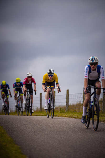 Four men racing on a road, one wearing blue and white.