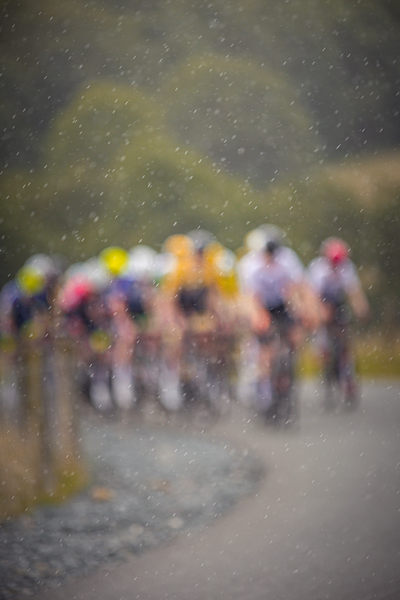 A group of men are riding their bikes on a wet road.