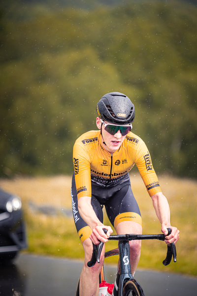 A man is riding a bike wearing a yellow and black cycling uniform.