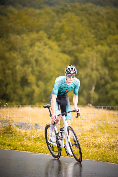 A male cyclist wearing blue and black gear prepares to compete in the Nederlands Kampioenschap.