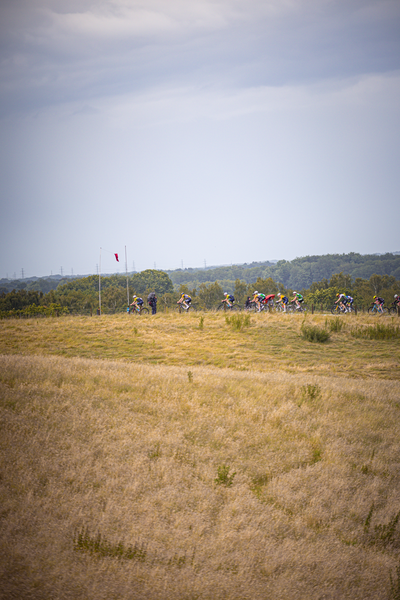 a field of people riding bikes, with flags flying above them.