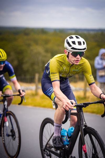 A pair of cyclists competing in a race, one with the number 24 on his back and both wearing helmets.