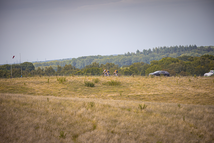 A group of riders race on a grassy field during the Nederlands Kampioenschap.