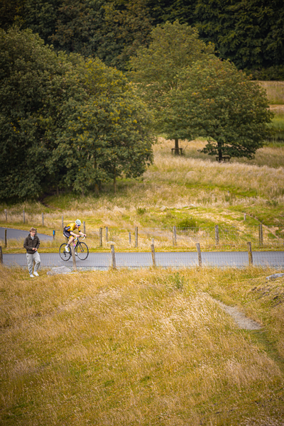 Two cyclists are riding down a road that is surrounded by trees and grass.