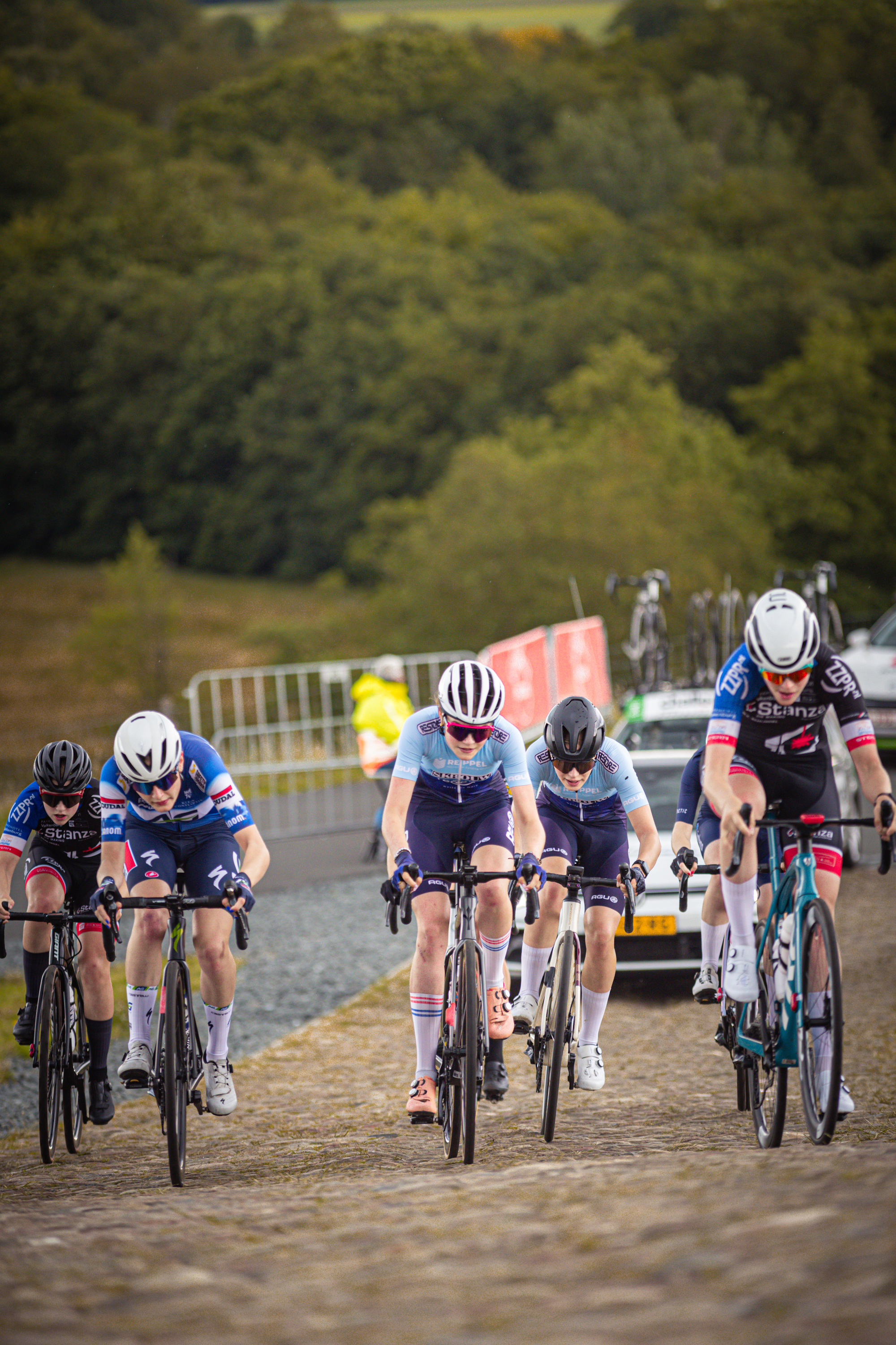 Four cyclists are participating in a race on a dirt track.