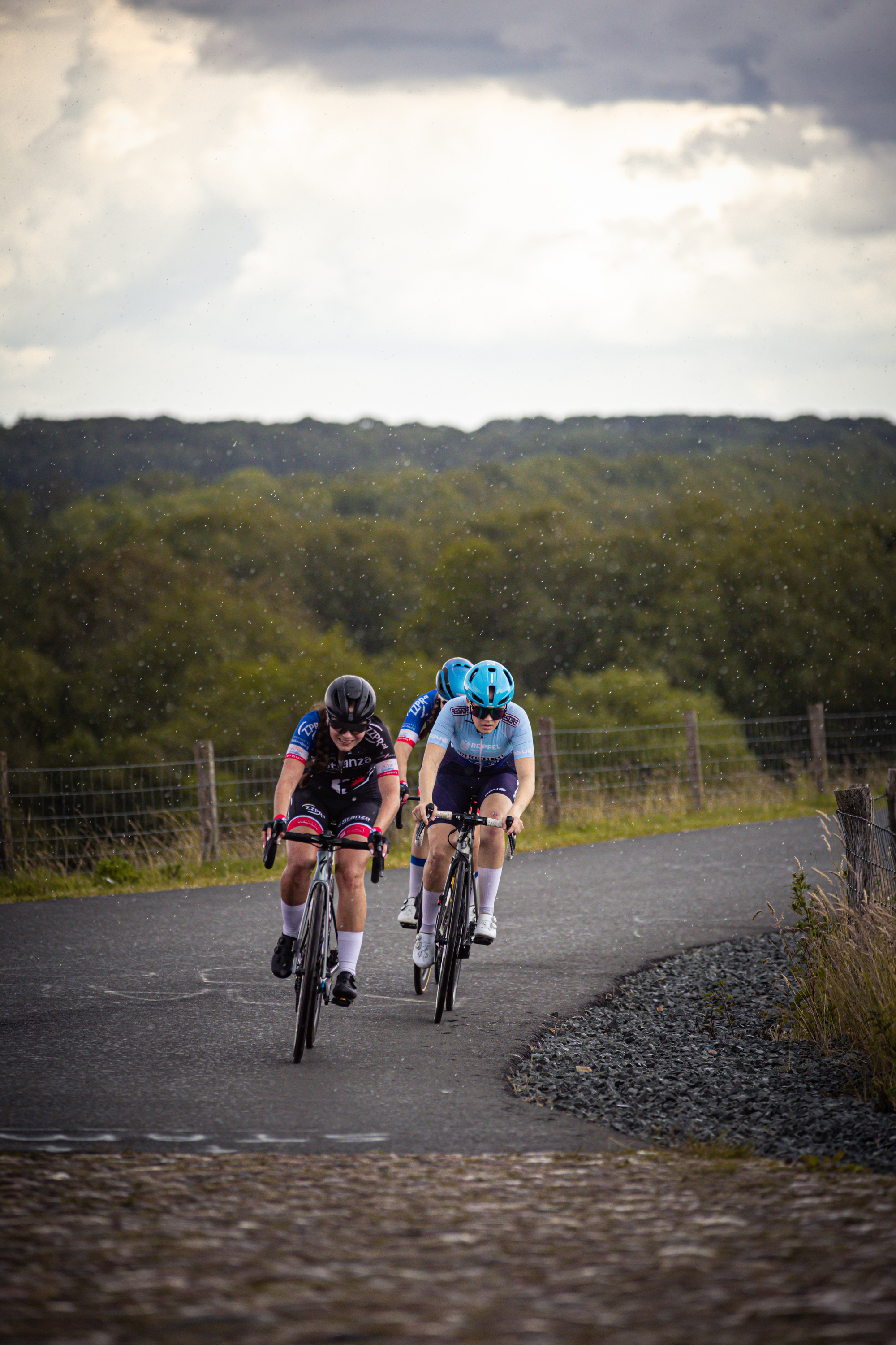 Two cyclists are racing on a road during the Dutch Junior Championships for women.