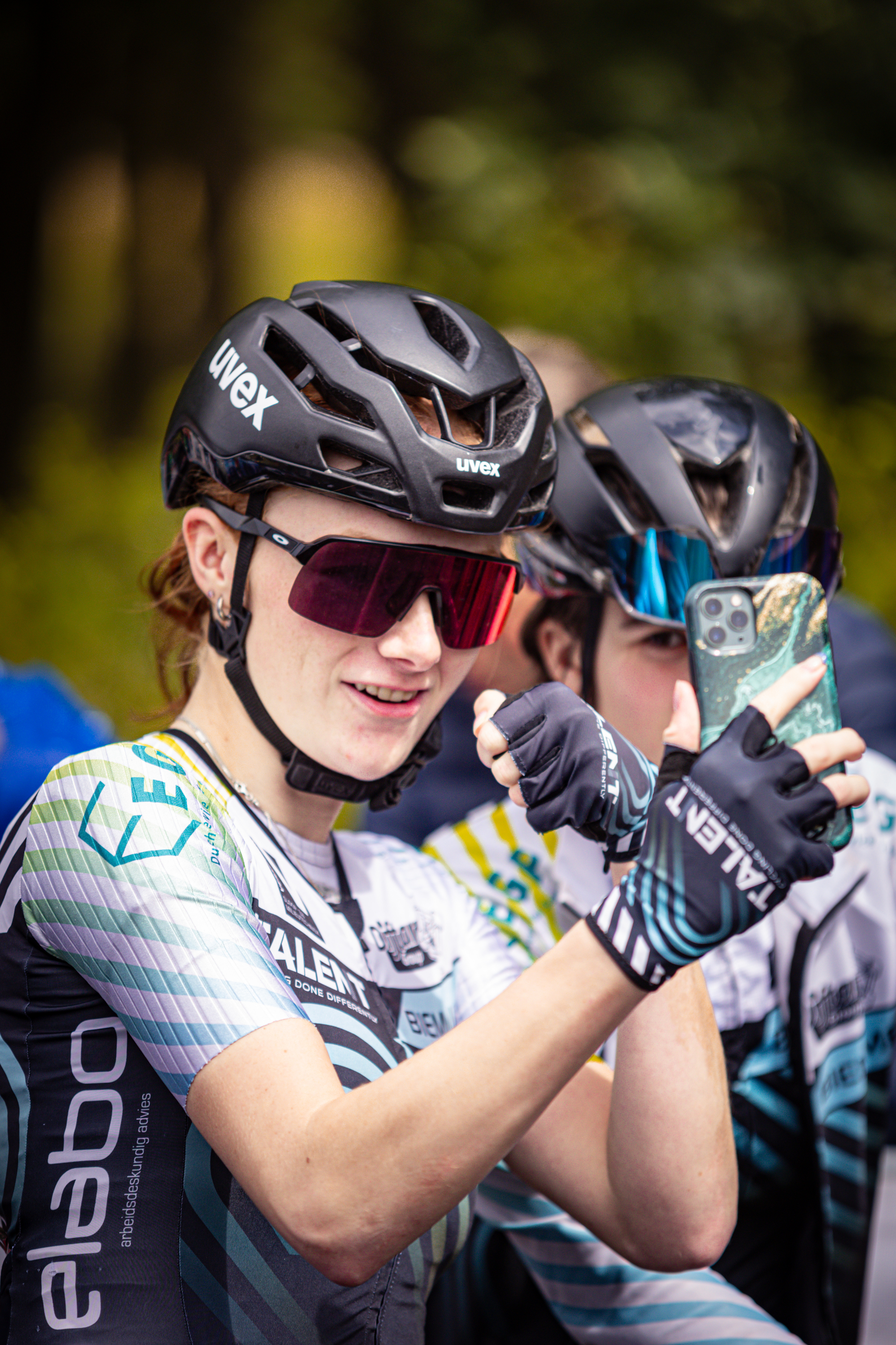 A girl with a blue jersey and a helmet wearing red glasses.