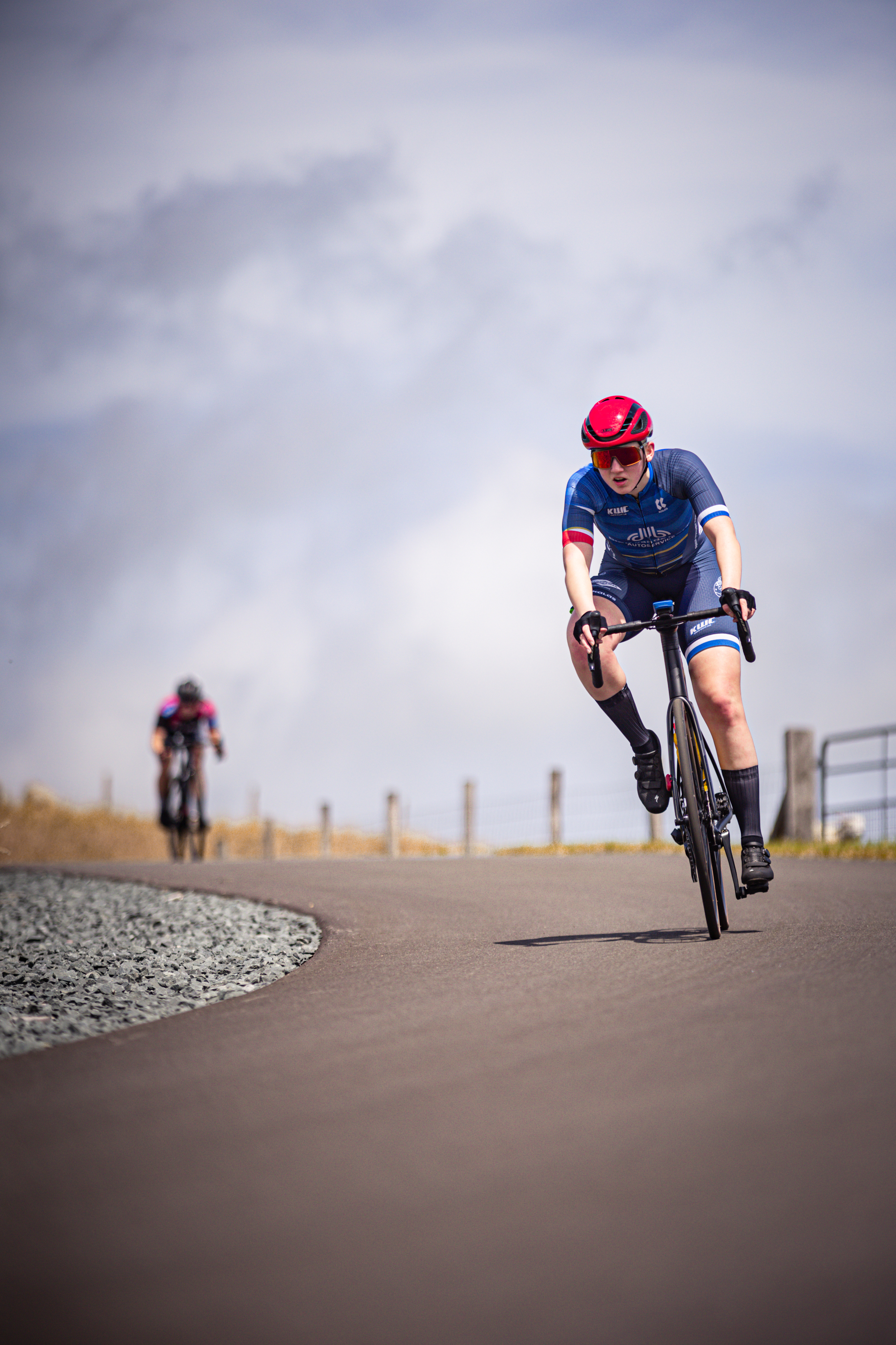 A person in a red helmet is riding a bicycle down the road.