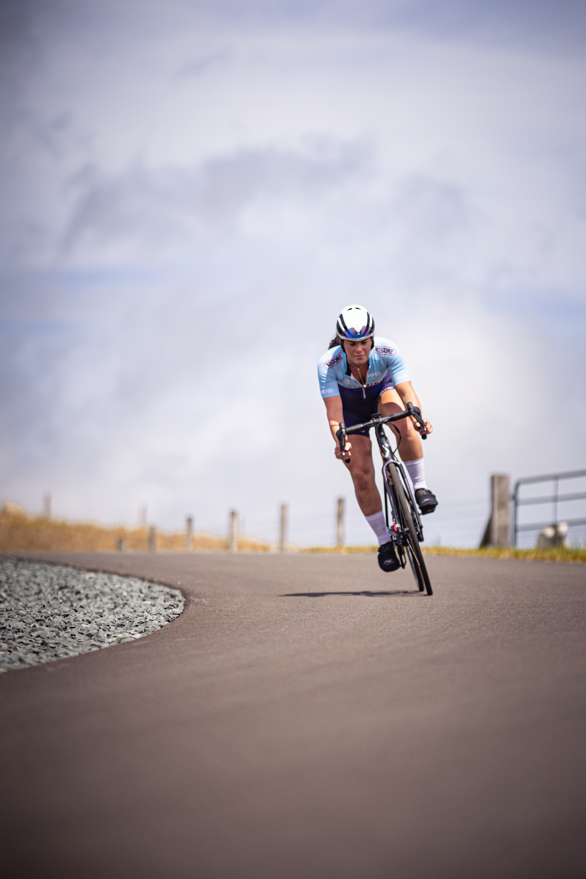 A woman riding a bike on the road for the Nederlands Kampioenschap.