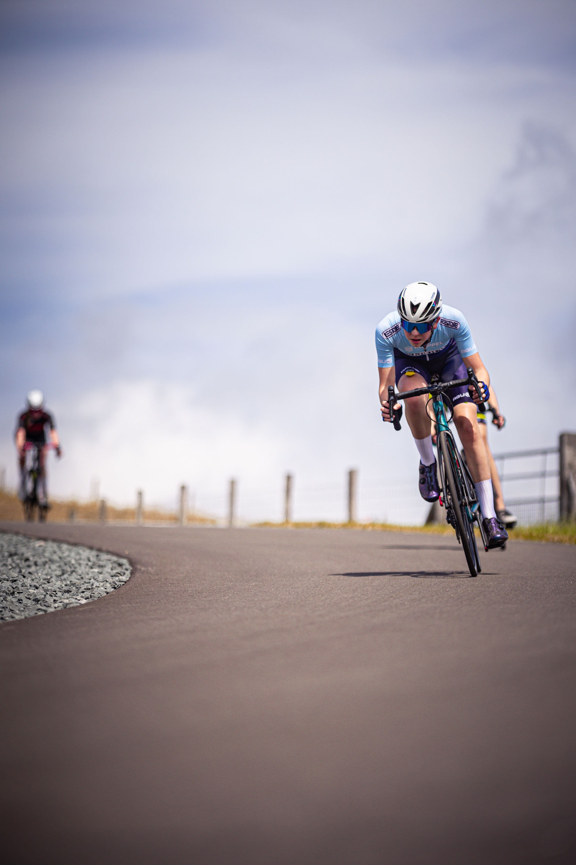 Two people are racing on their bikes on a cloudy day.