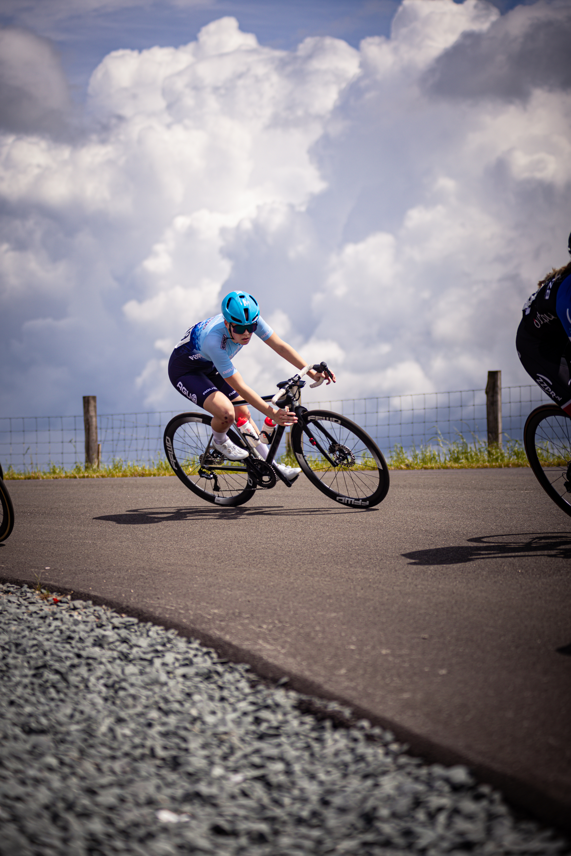 A woman wearing a blue helmet is riding a bike on a road.