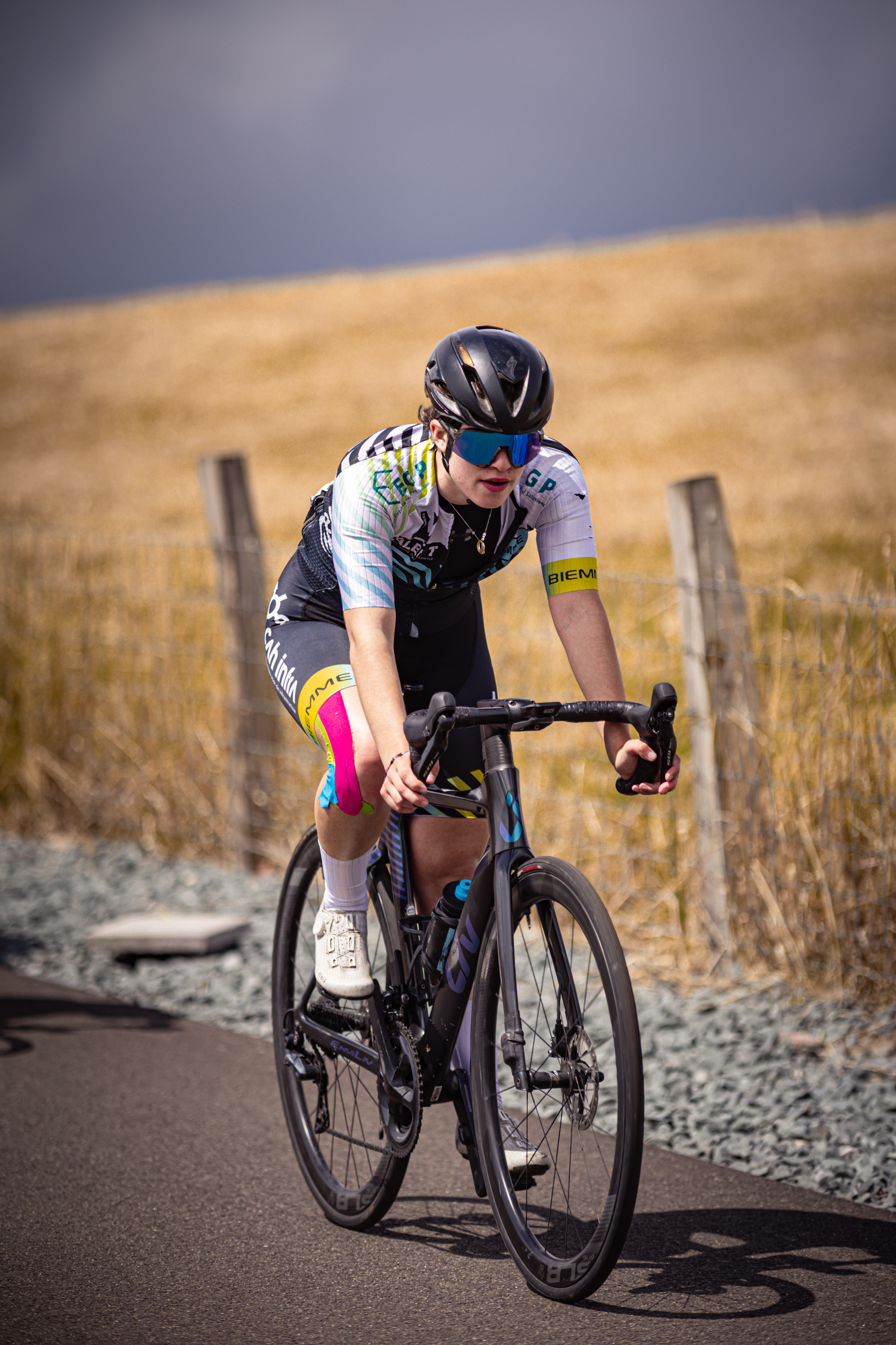 A young woman riding a bike with the number 3 on her jersey.