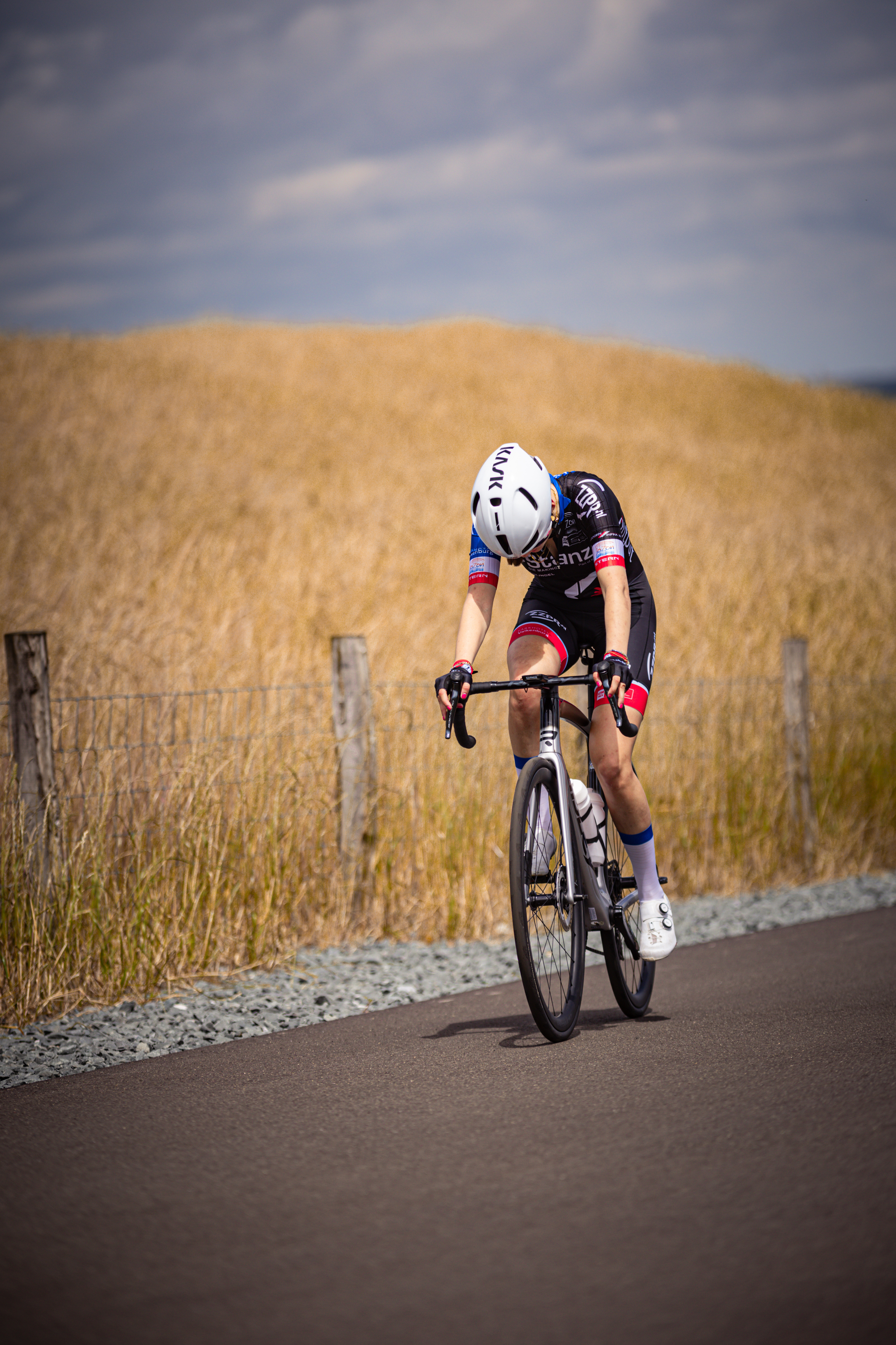 A woman is wearing a cycling suit and riding her bike on the road.