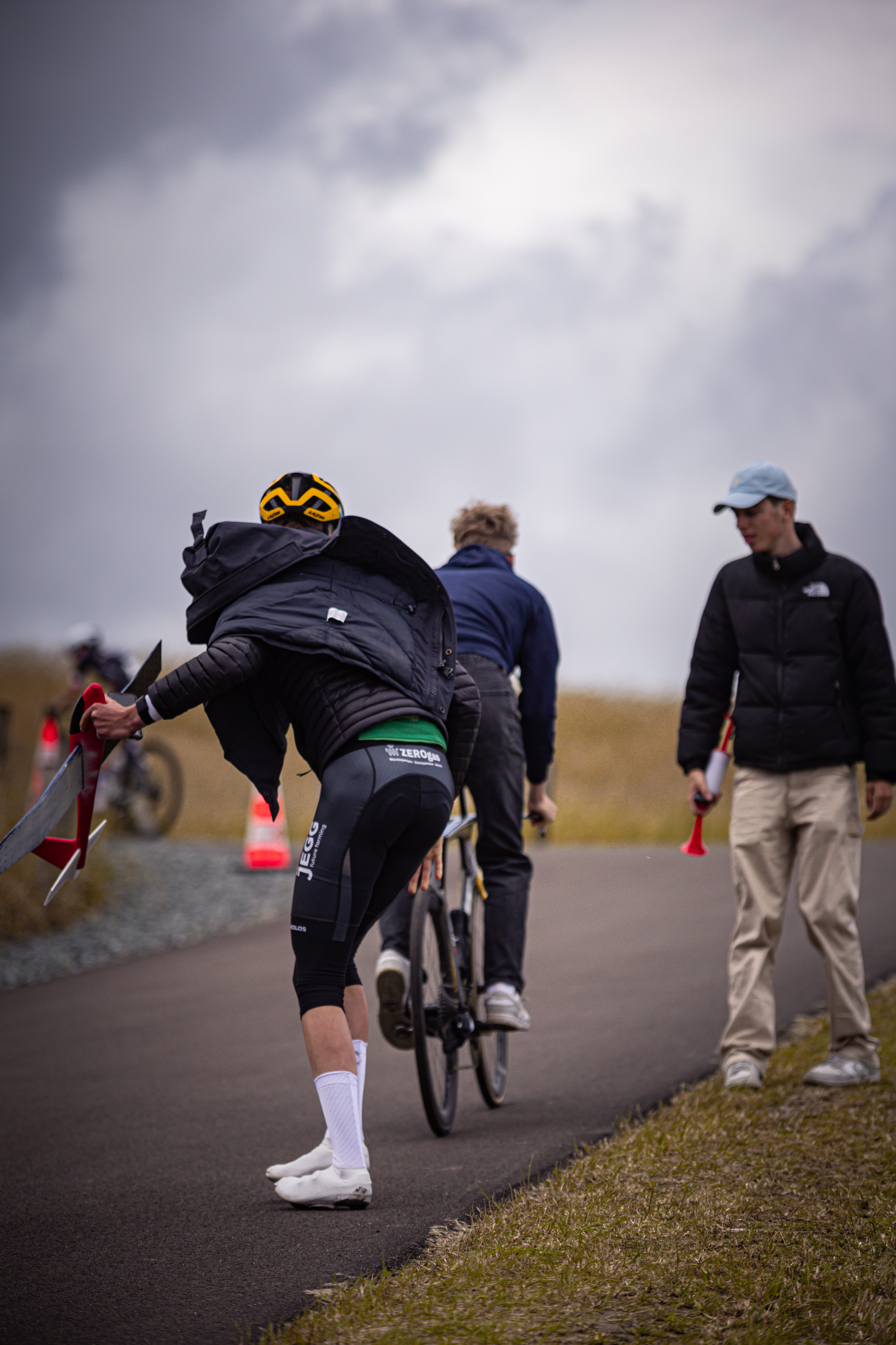 A person wearing a yellow helmet holding an orange flag.