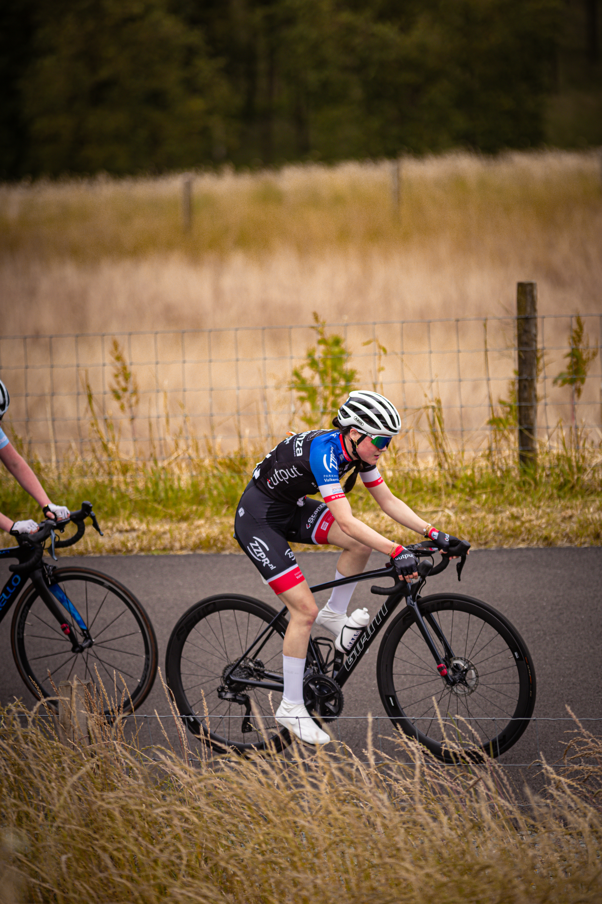 Two people on bikes, the one in blue is wearing number 1.