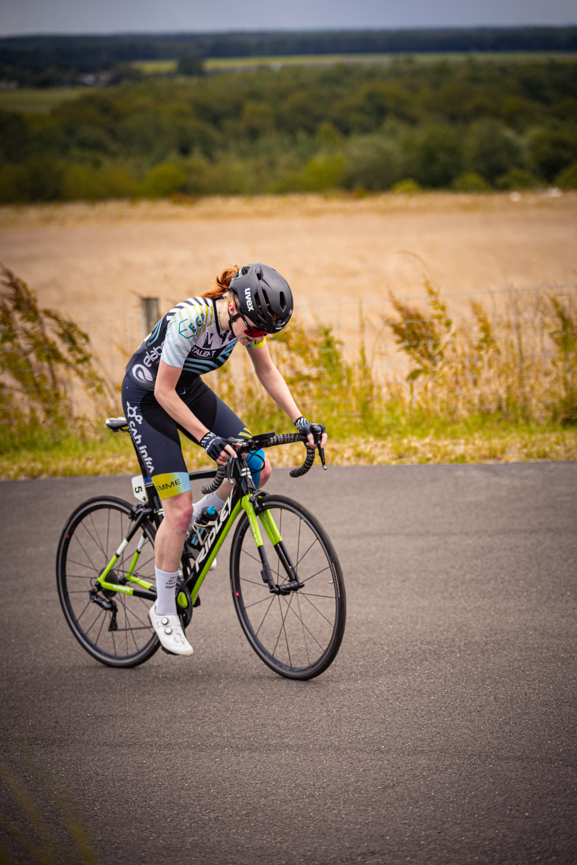 A female cyclist with the number 16 on her jersey, riding a bicycle.