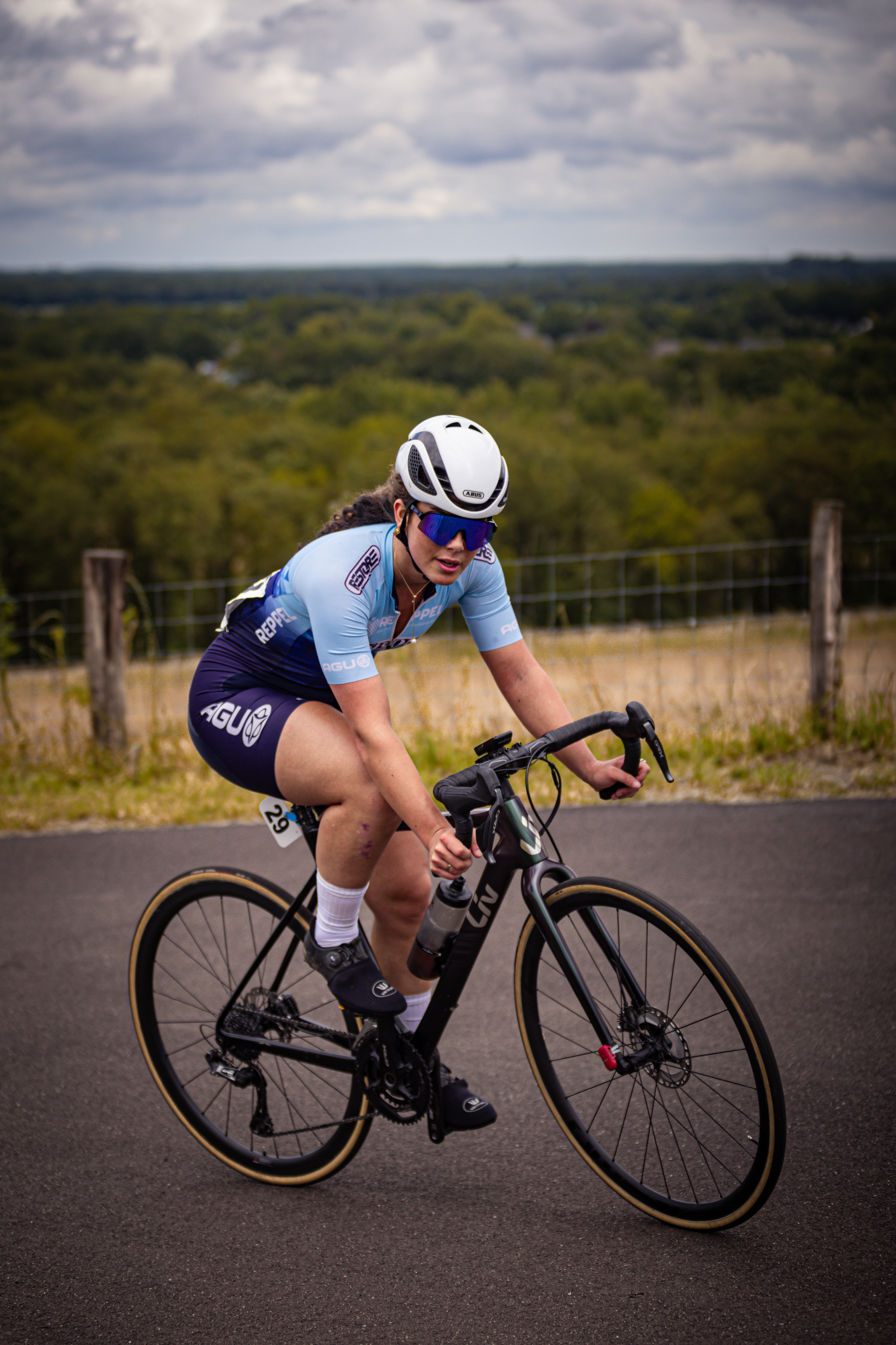 A cyclist wearing a blue shirt and black shorts, racing on a track.