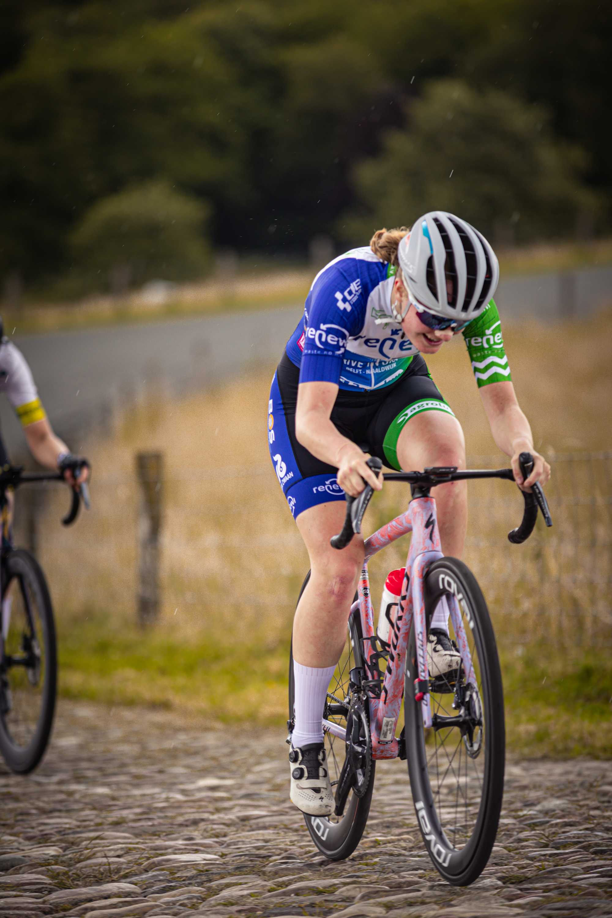 Two women are racing bikes on a track at the Nederlands Kampioenschap.