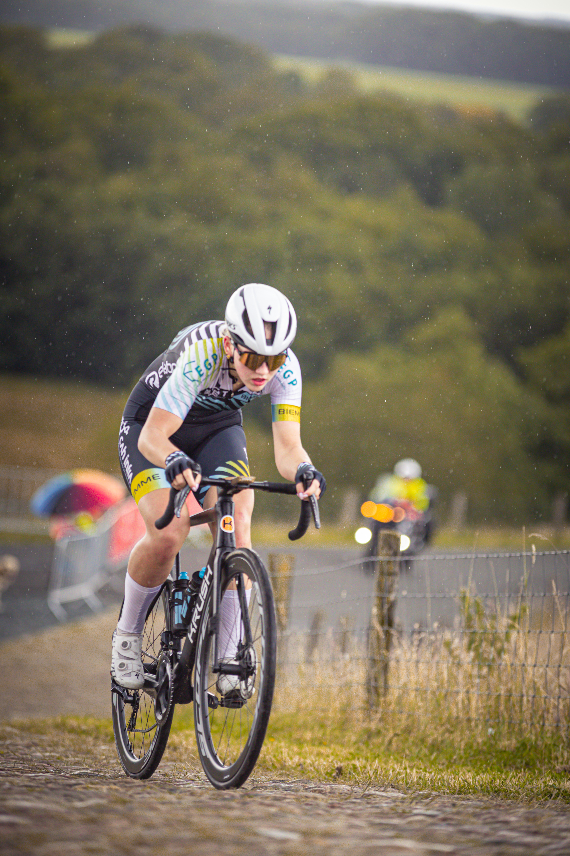 A cyclist wearing a white helmet is riding on a dirt road.