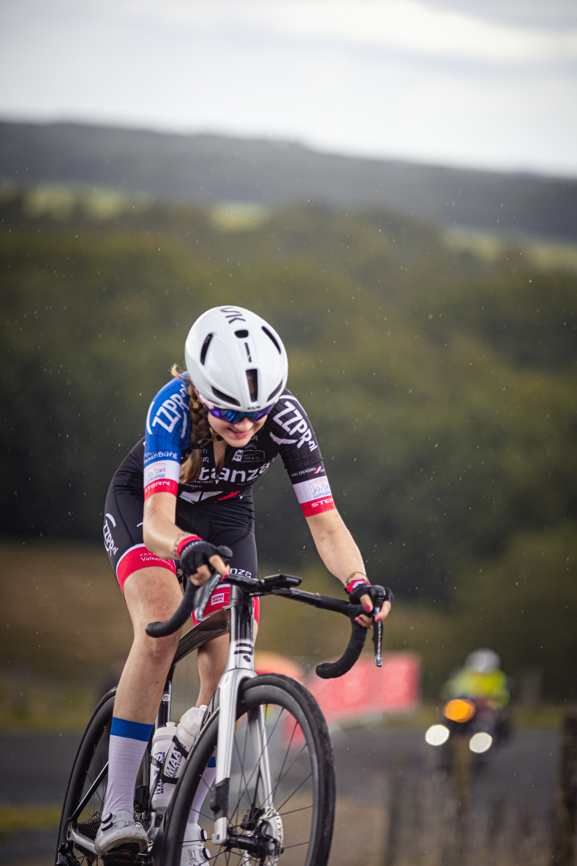 A female cyclist wears a blue and black uniform sponsored by Giant.