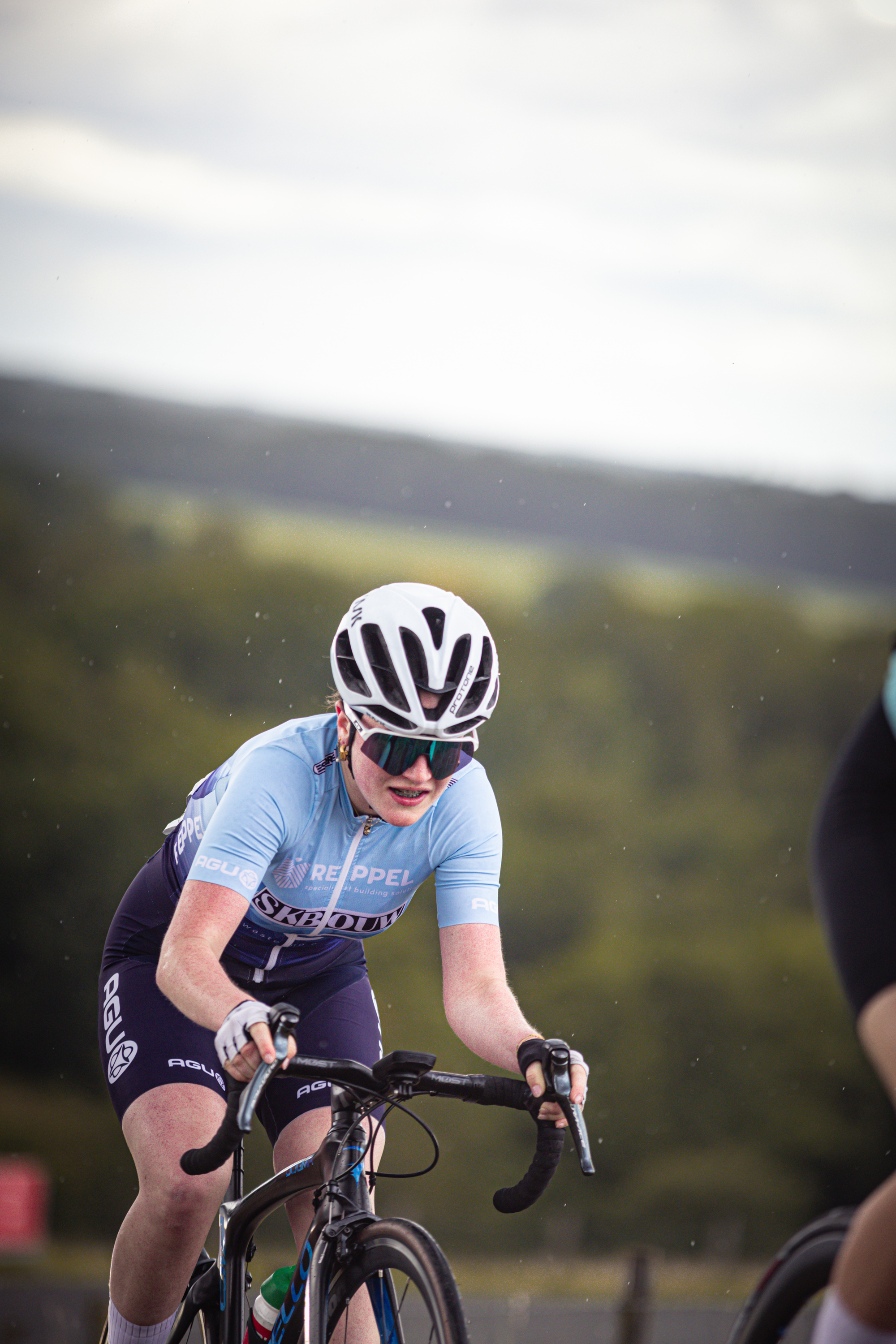 A cyclist is wearing a blue shirt with the word wielrennen on it.