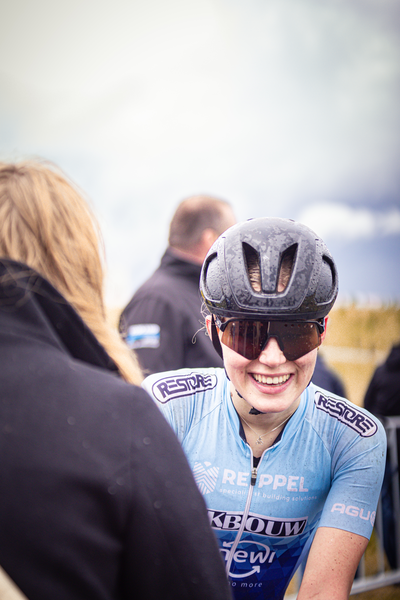 A young girl wearing a blue jersey and helmet, with the word Repel written on it. She is smiling at someone.