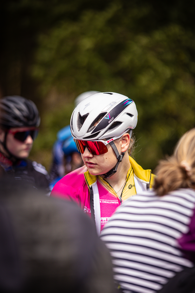 A young person wearing a pink shirt and a silver bike helmet.