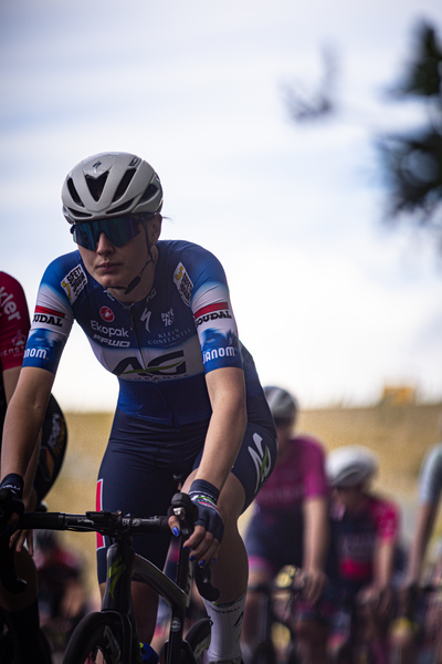 A woman riding a bike with the letters AK on her shoulder.