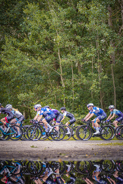 A group of people riding bicycles and one wearing a bib that reads "Junioren Dames".